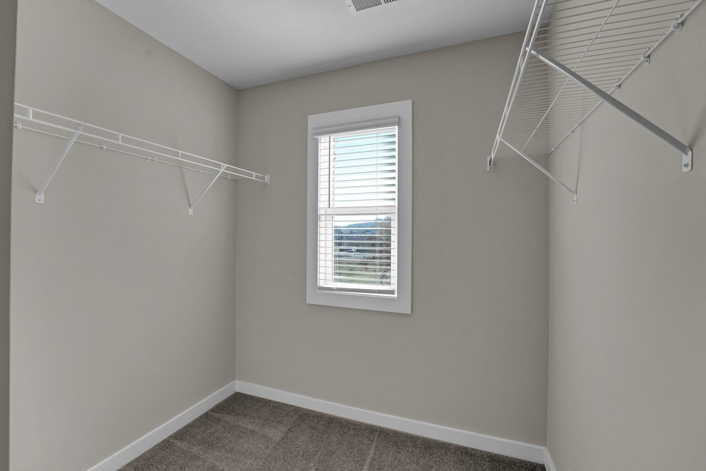 an empty closet with two hanging racks and a window