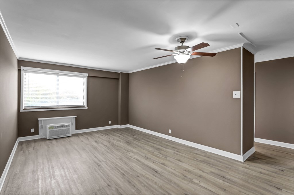 an empty living room with brown walls and a ceiling fan