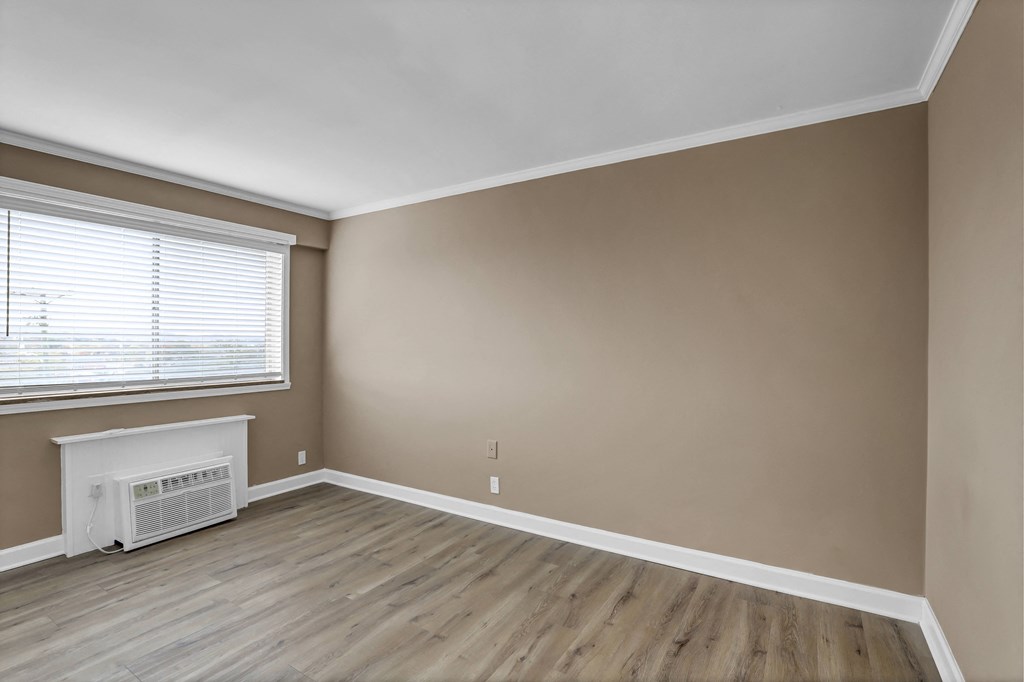 an empty living room with wood floors and a window