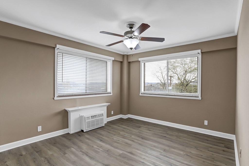 an empty room with a ceiling fan and two windows