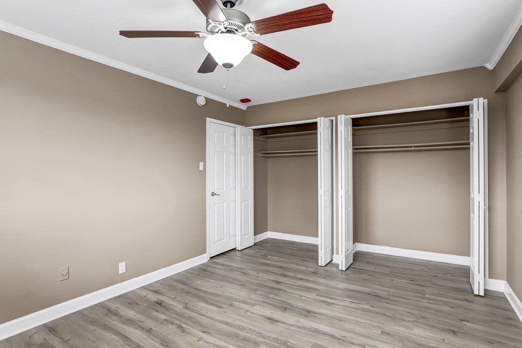 an empty bedroom with a ceiling fan and two closets