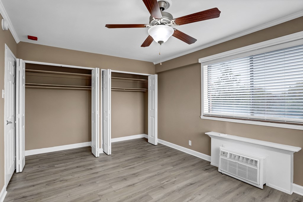 an empty bedroom with two closets and a ceiling fan