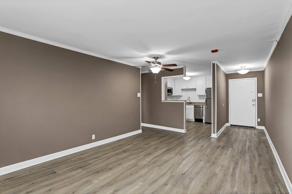 an empty living room with wood floors and a ceiling fan