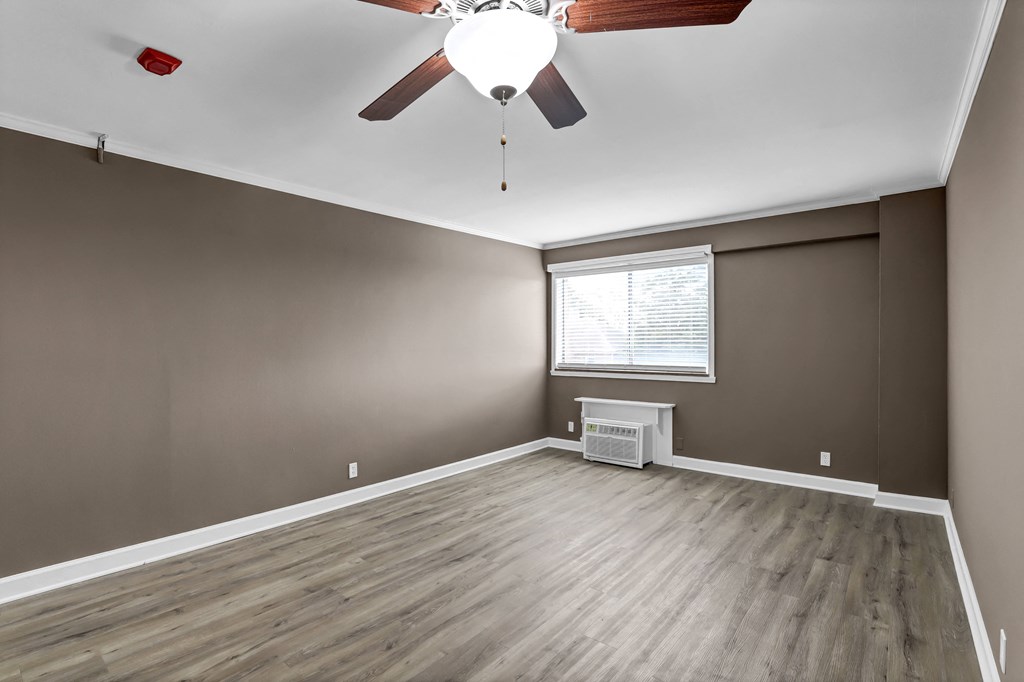 an empty living room with a ceiling fan and a window