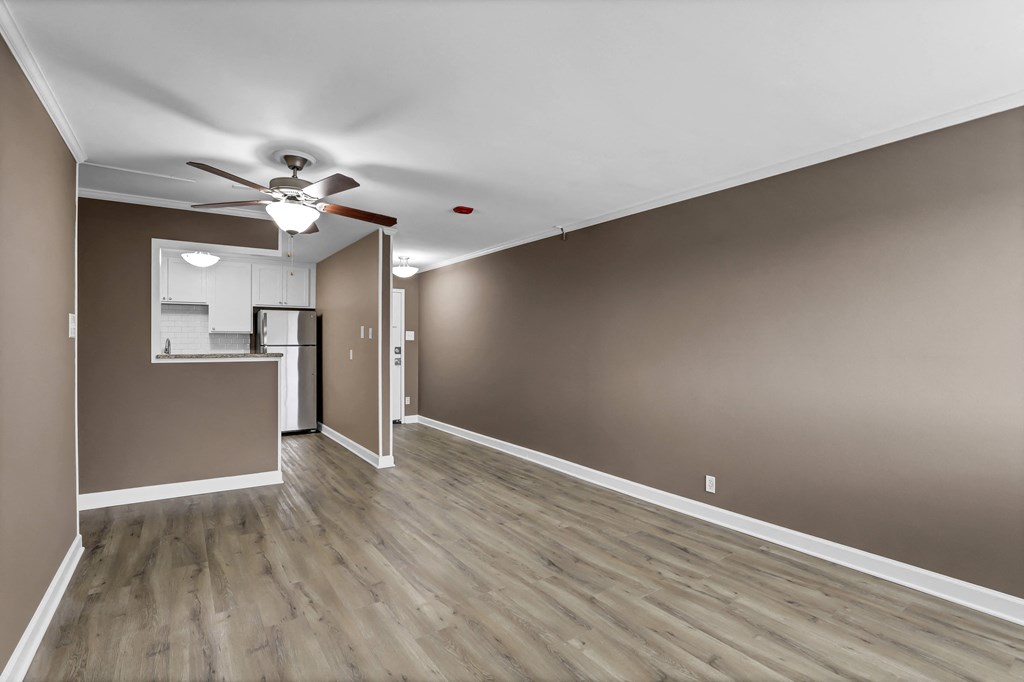 an empty living room with wood floors and a ceiling fan