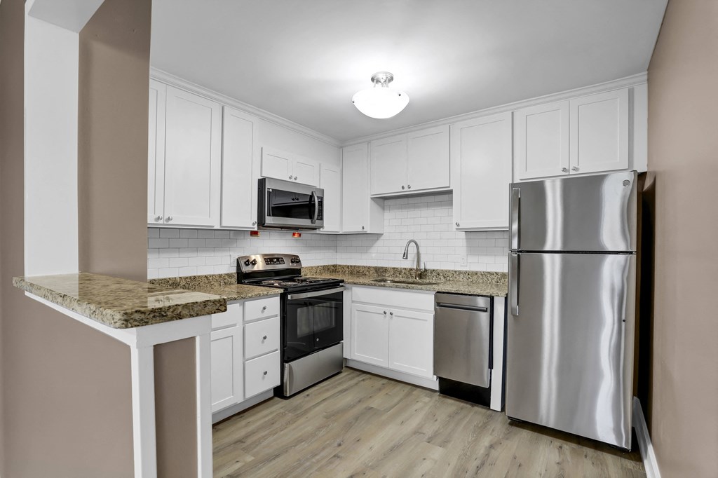 a kitchen with white cabinets and granite counter tops and stainless steel appliances