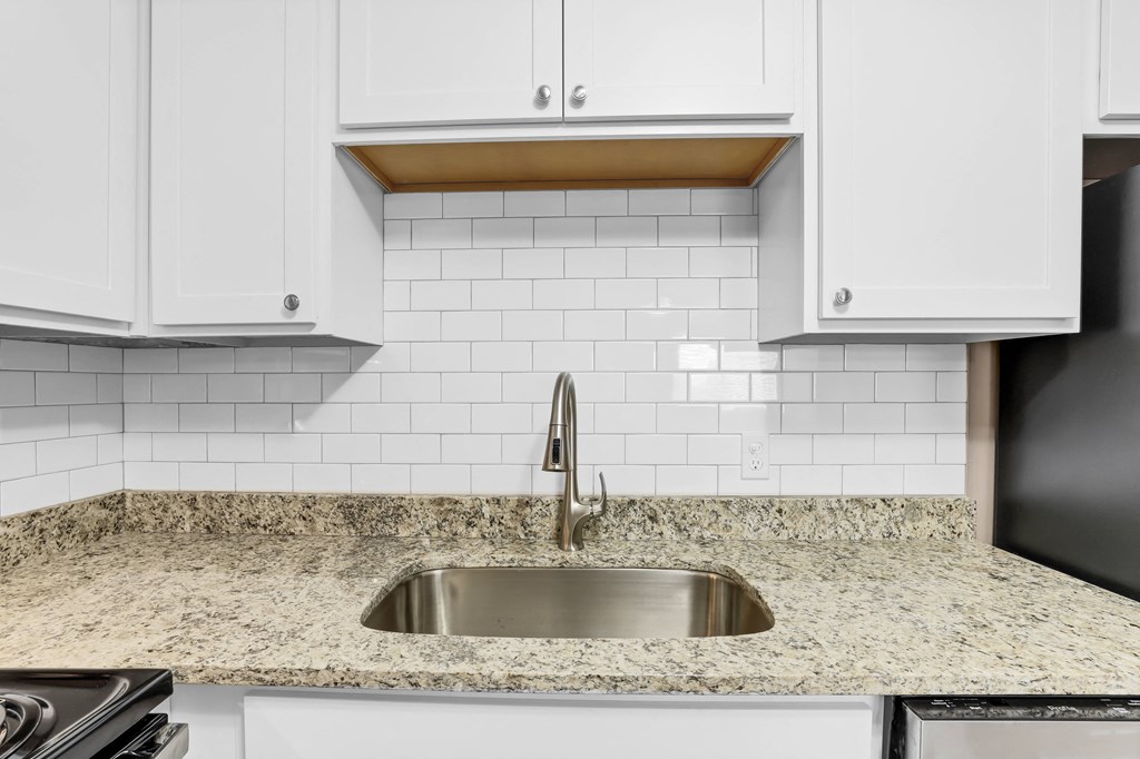 a white kitchen with a sink and white cabinets