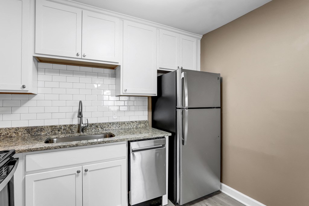 a kitchen with white cabinets and a stainless steel refrigerator
