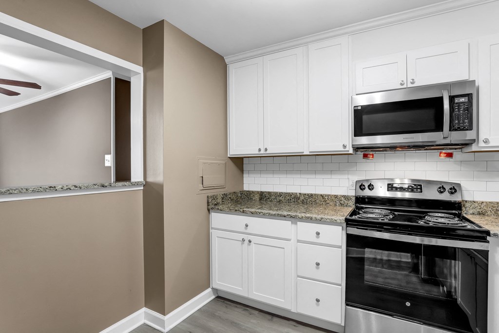a kitchen with white cabinets and a stove and a microwave