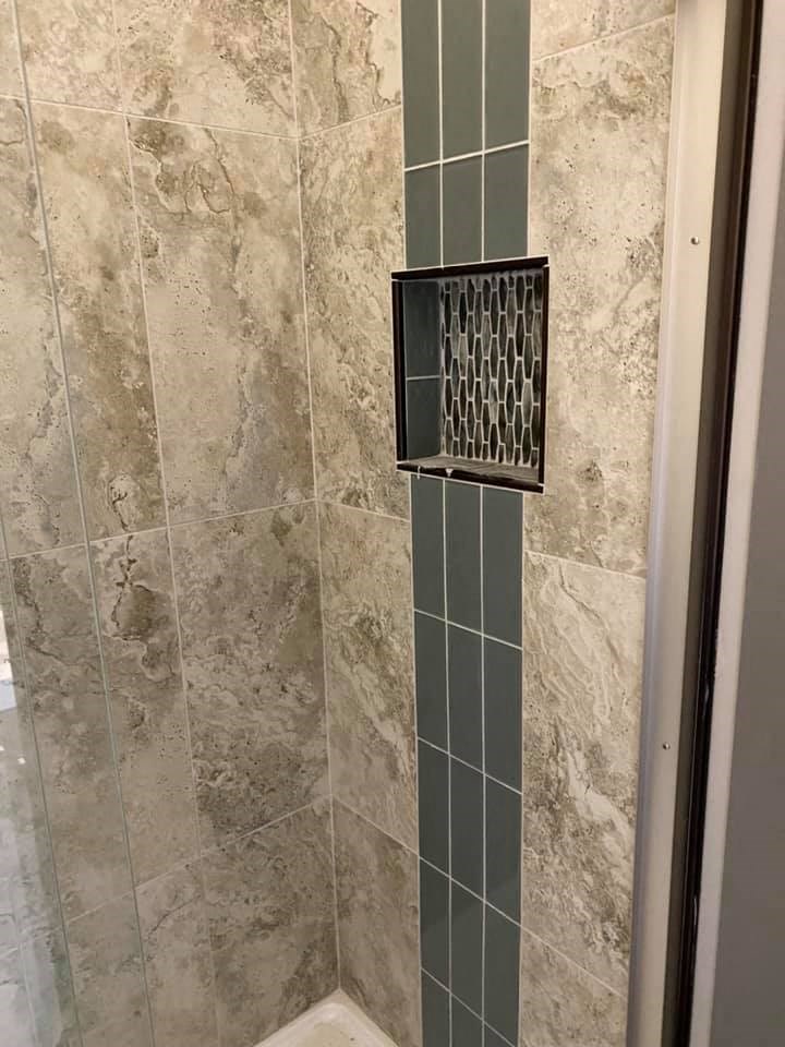 a bathroom with a shower door and a tiled wall