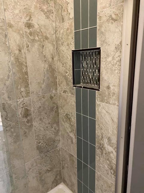 a bathroom with a shower door and a tiled wall