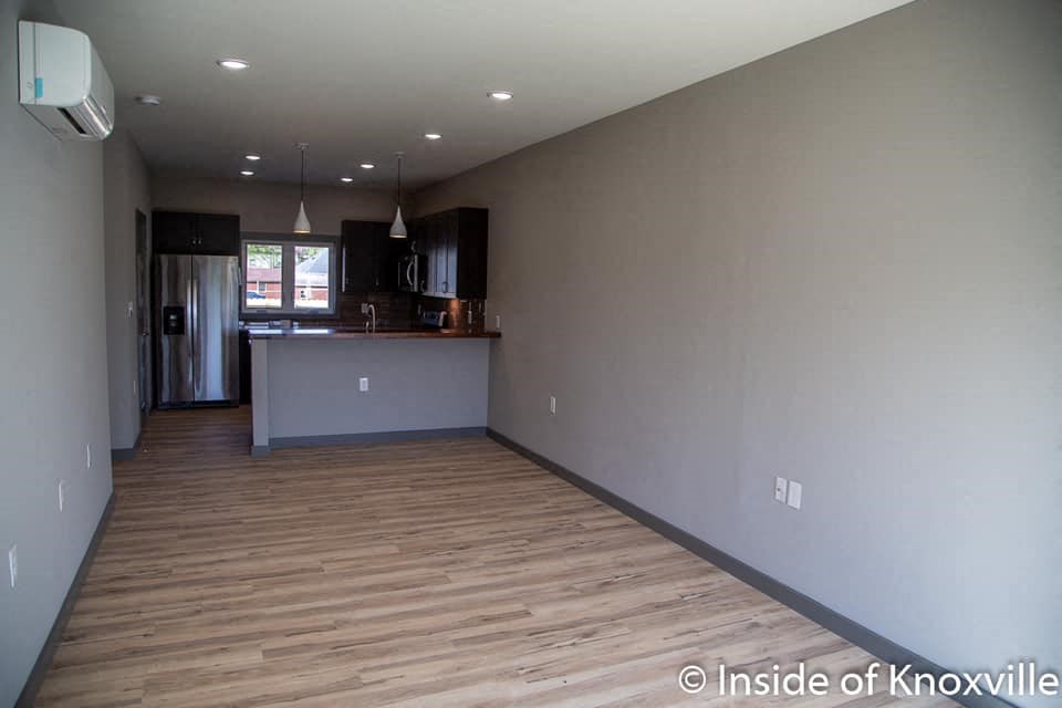 a living room with a kitchen and a wooden floor