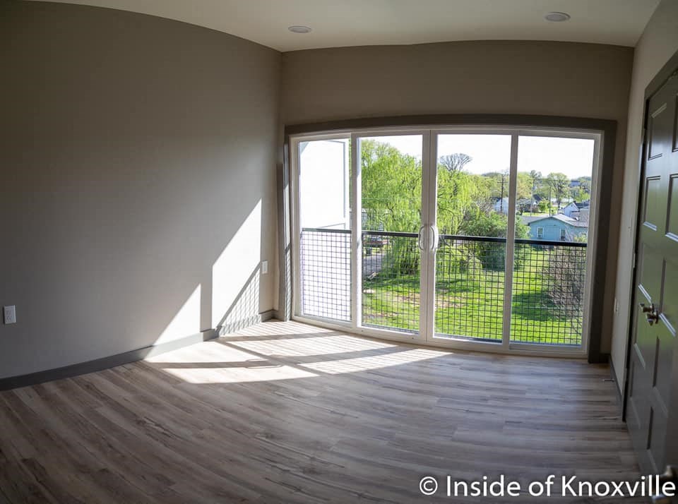 an empty living room with a balcony and a large window