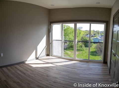 an empty living room with a balcony and a large window