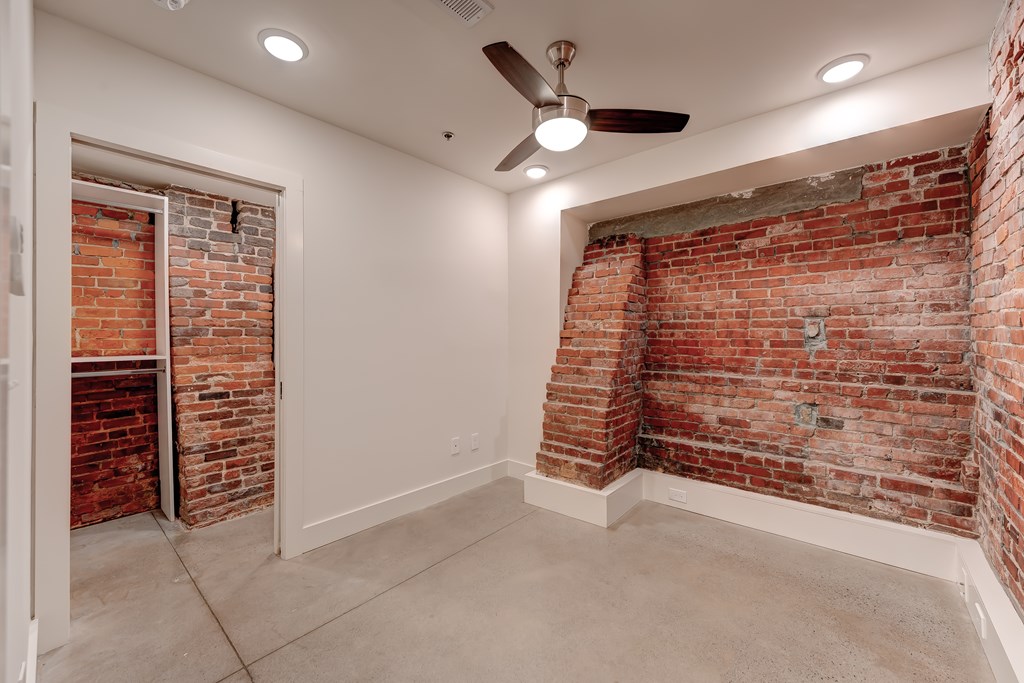 A room with a brick wall and a ceiling fan.