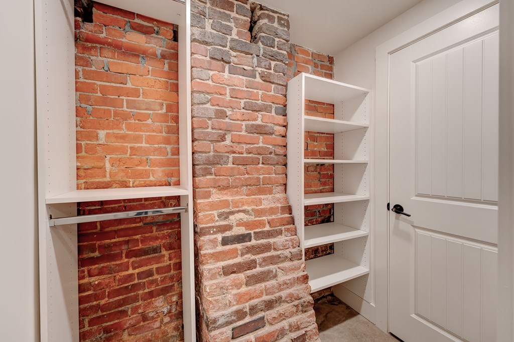 A white shelving unit is built into a brick wall.