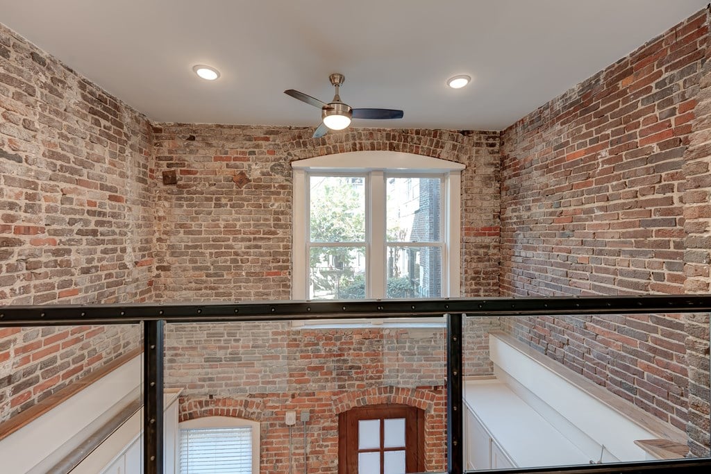 A room with a brick wall and a ceiling fan.