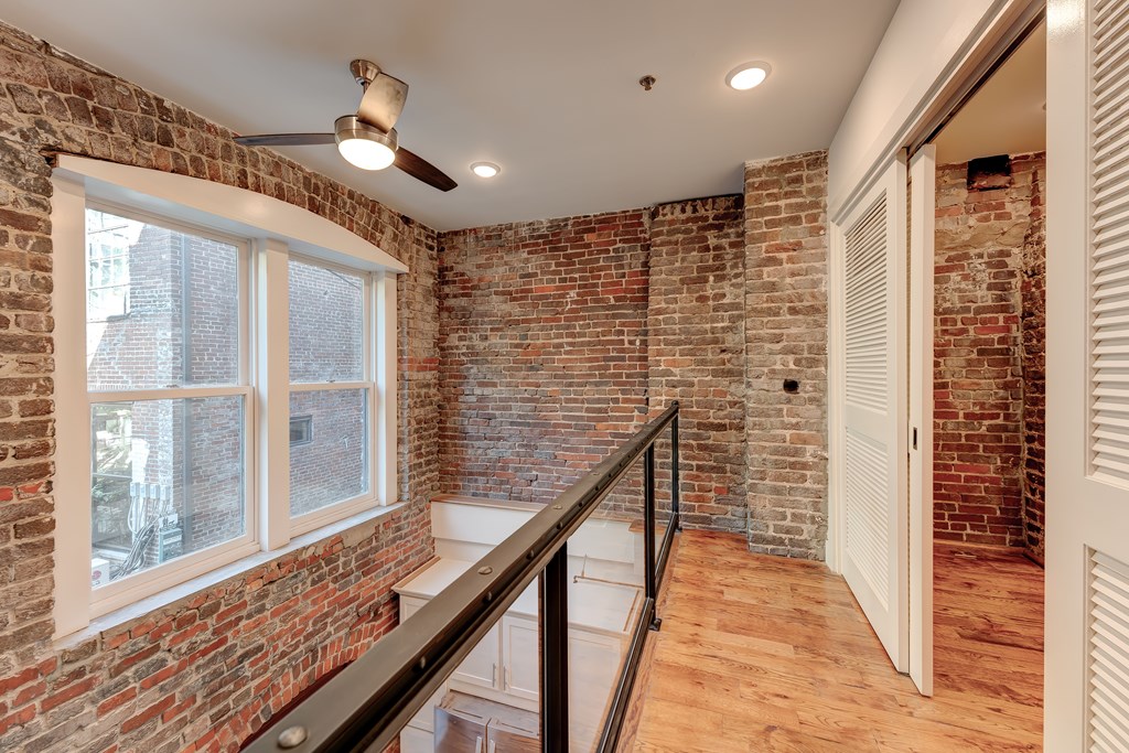 A room with a brick wall and a ceiling fan.