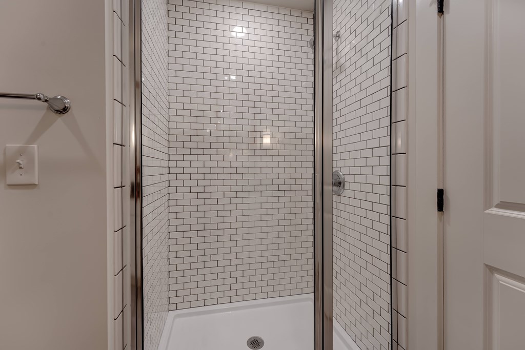 A white tiled shower with a white tub and a white door.