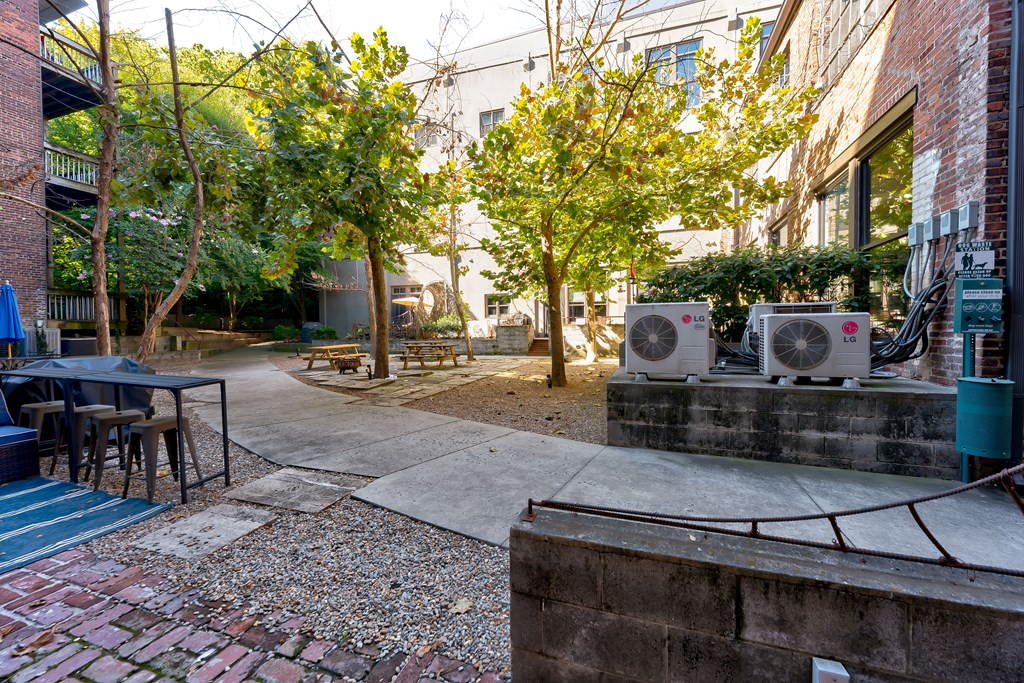 A courtyard with a brick wall and a tree with a metal structure on it.