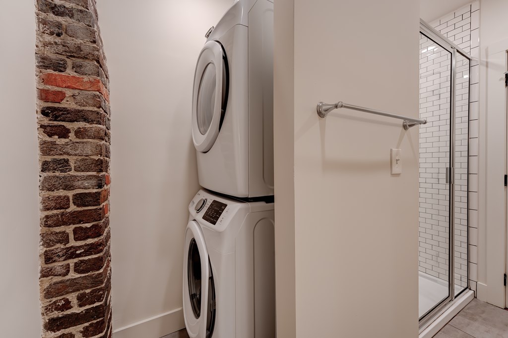 A washing machine is placed next to a brick wall.