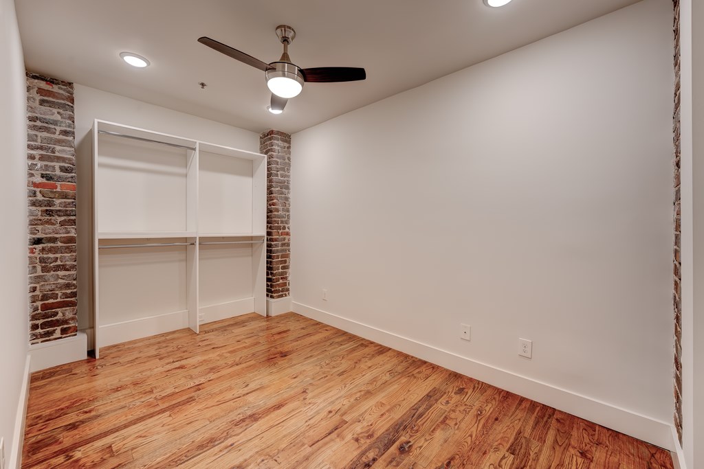A room with a ceiling fan and wooden flooring.