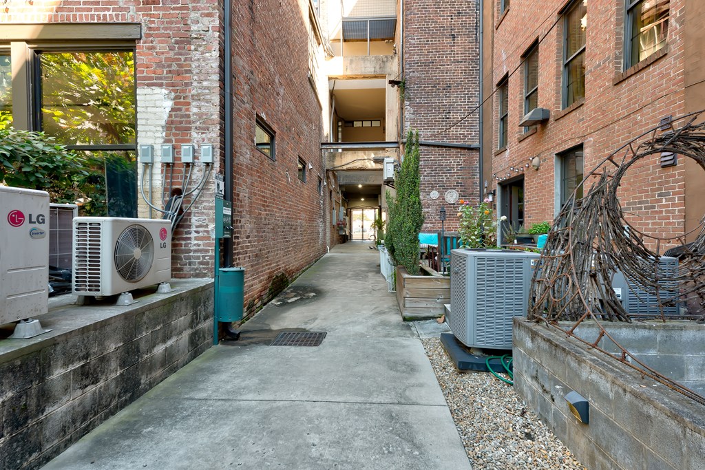 A narrow alley with brick buildings and air conditioning units on the side.