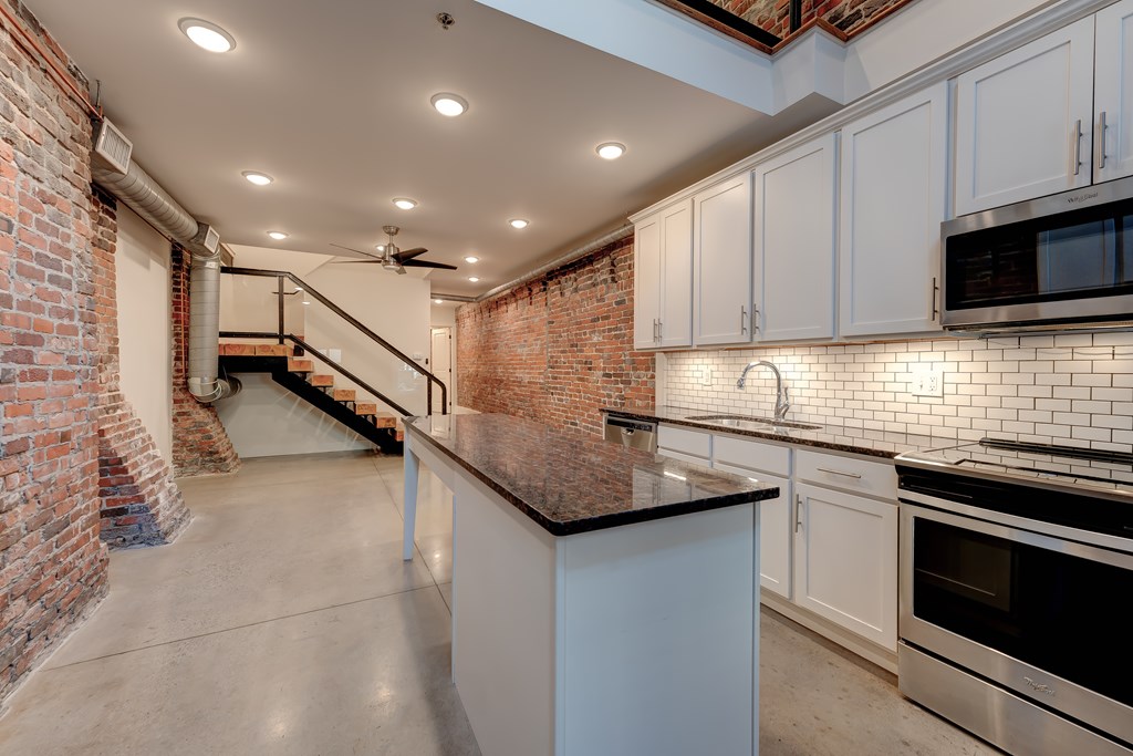 A kitchen with a brick wall and a ceiling fan.