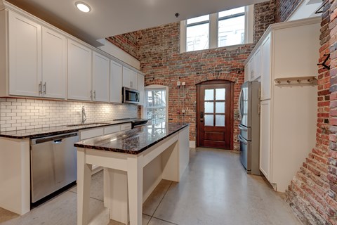 A kitchen with white cabinets and a brick wall.