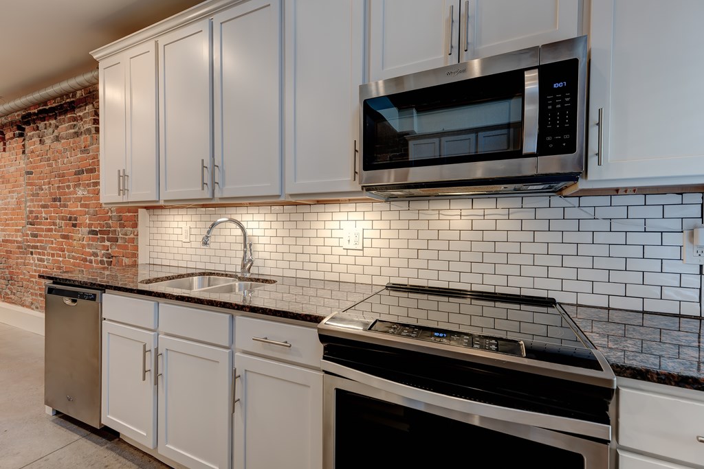 A kitchen with white cabinets and a black stove top oven.