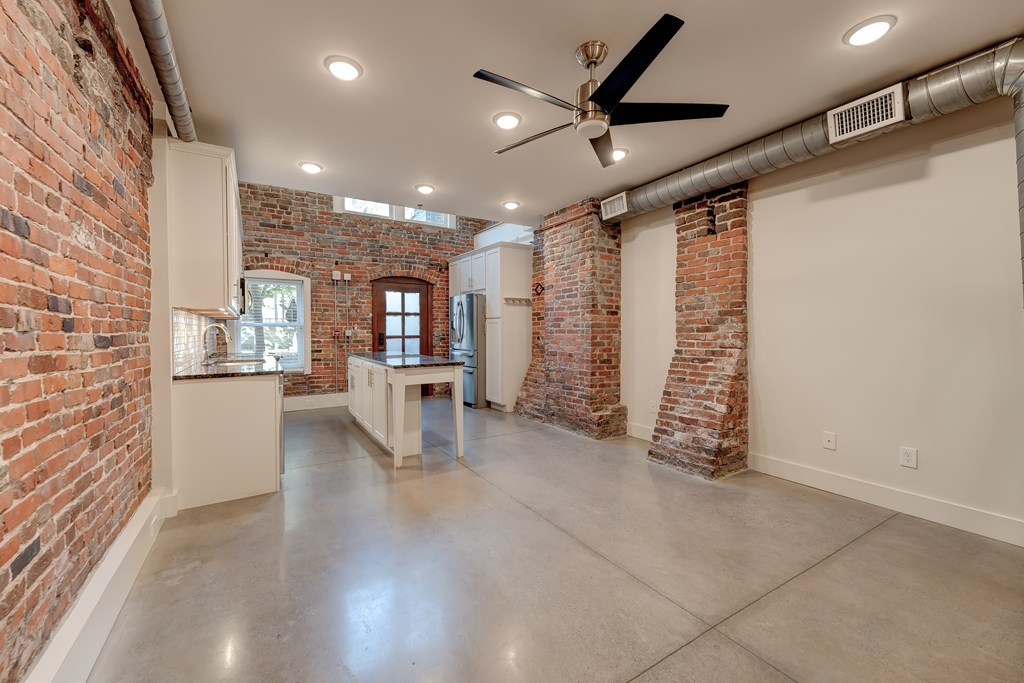 A room with a ceiling fan and brick walls.