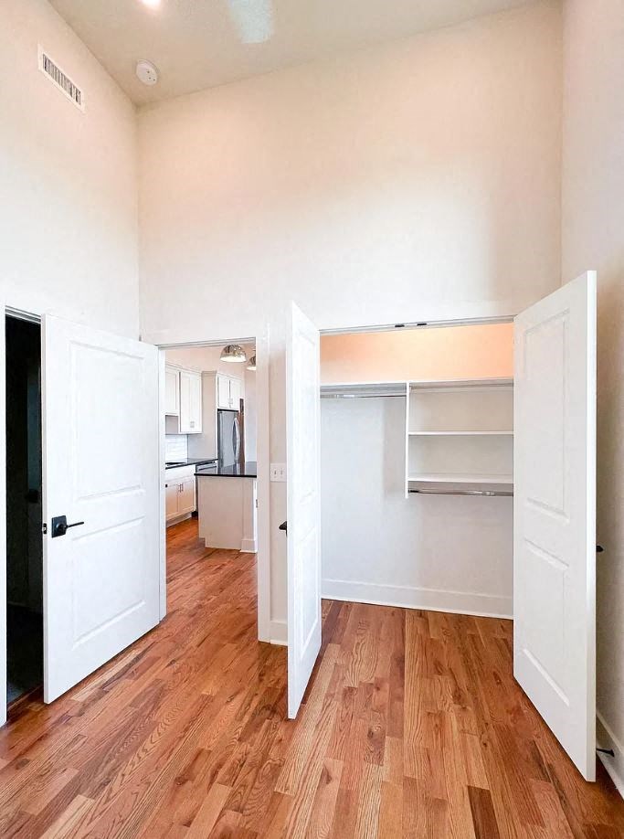 a bedroom with two doors and a kitchen in the background