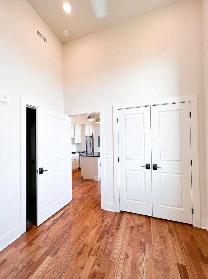 a room with two doors and a kitchen in the background