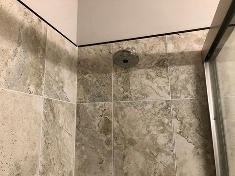 a shower with a shower head in a tiled bathroom
