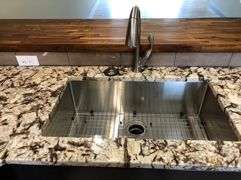 a stainless steel sink with a wooden counter top