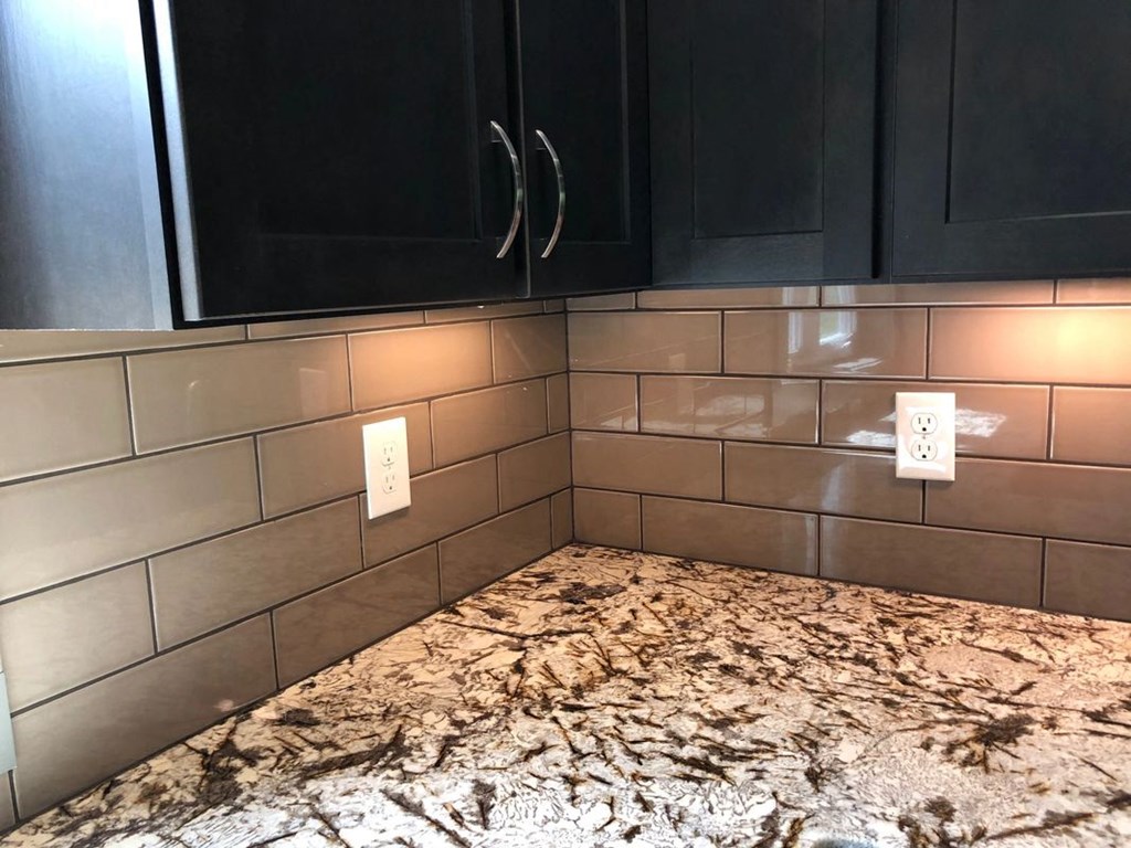 a tiled kitchen with black cabinets and a marble counter top