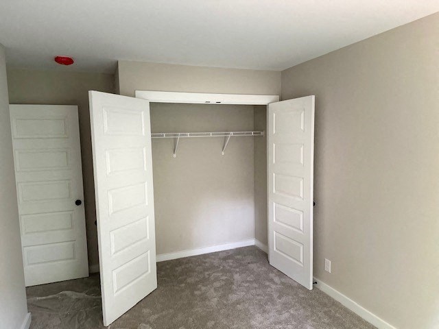 an empty bedroom with a closet and two doors