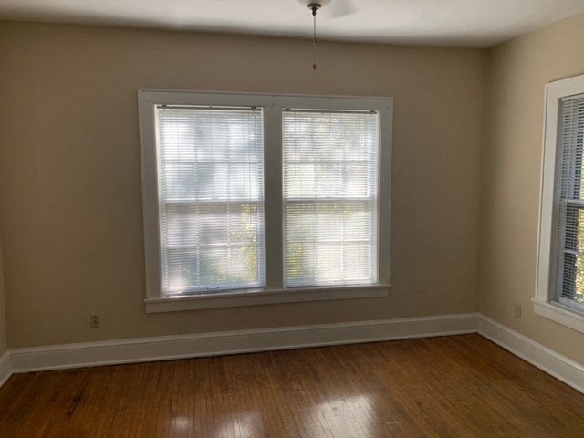 a living room with two windows and a hard wood floor