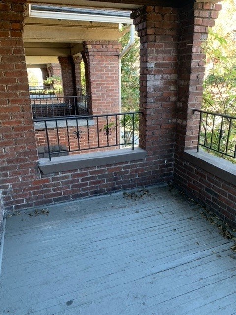 a balcony with a brick wall and a wooden floor