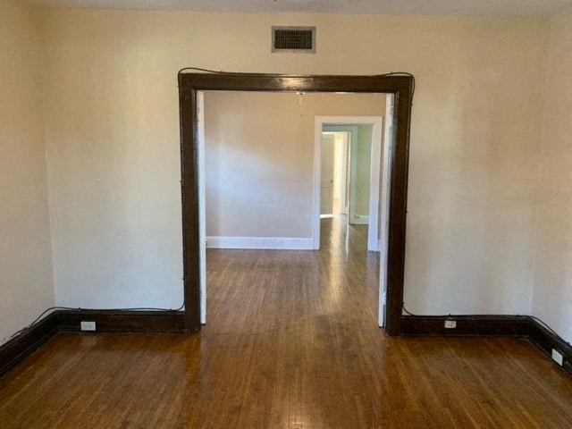 an empty room with a wooden floor and a mirror