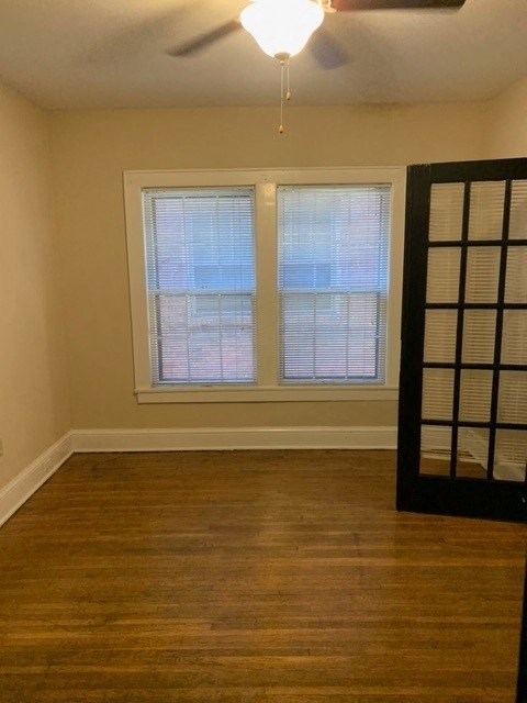 a empty room with three windows and a ceiling fan
