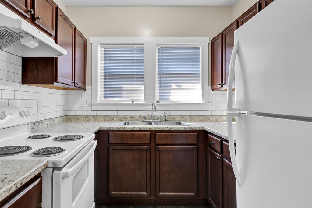 an empty kitchen with white appliances and brown cabinets