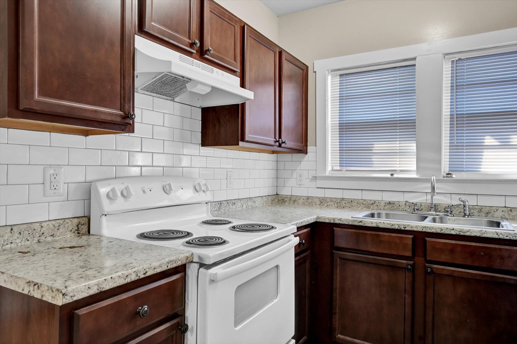 an updated kitchen with white appliances and granite counter tops