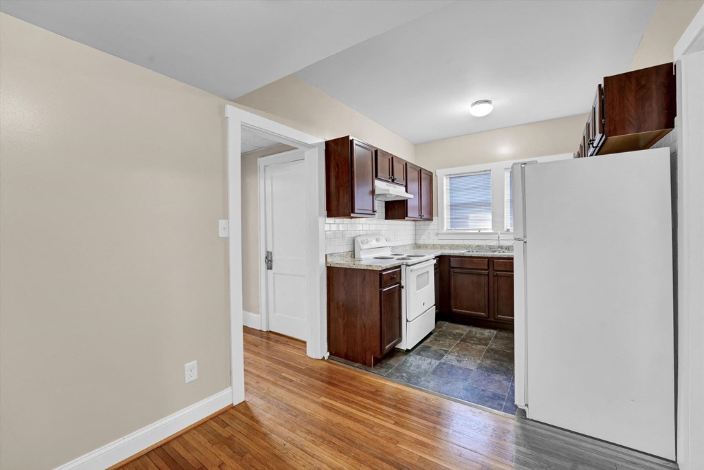 a renovated kitchen with white appliances and wooden floors