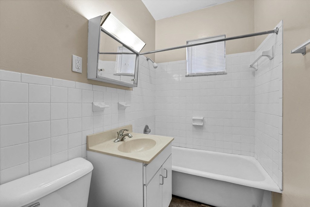 a white bathroom with a sink and a tub and a mirror