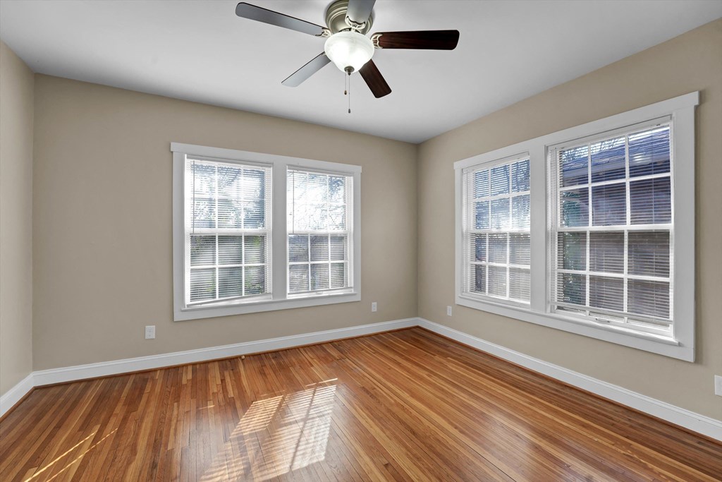 an empty living room with wood floors and a ceiling fan
