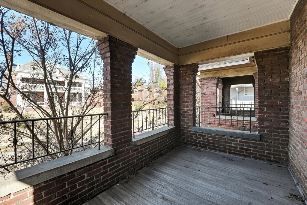 the porch of a brick apartment building with a wooden deck