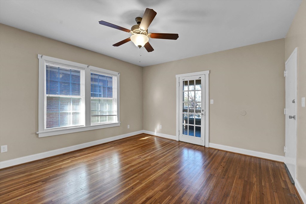 an empty living room with wood floors and a ceiling fan