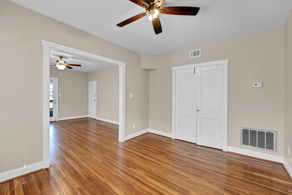 an empty living room with wood floors and a ceiling fan