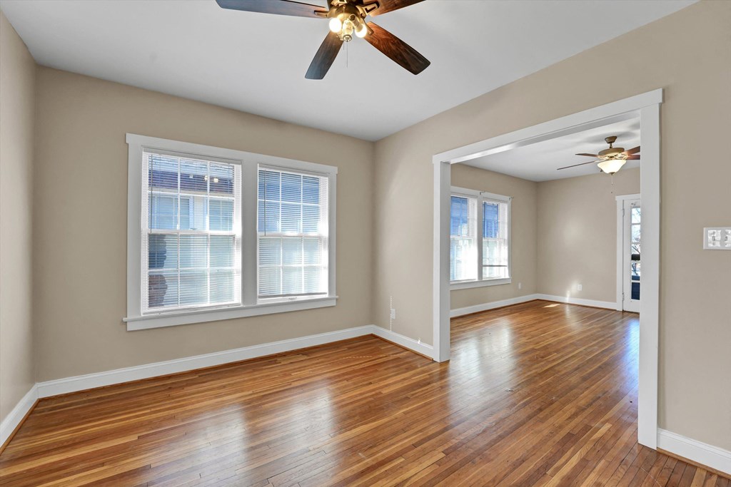 an empty living room with wood floors and a ceiling fan